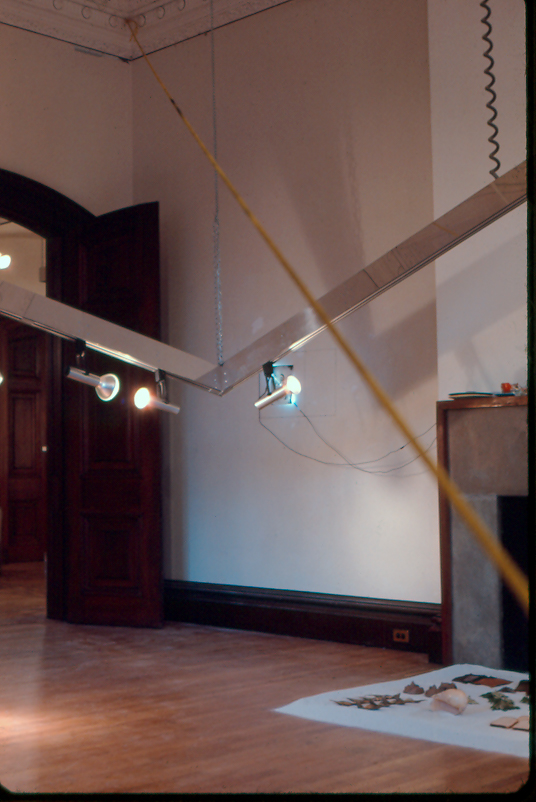 Contemporary artist Harry Anderson offten used what he found in the space that he was exhibiting as elements.  Here he has taken the frame that held the exhibition lighting at the Woods-Gerry and lowered three corners of it so that visitors were forsed to interact with it.  Through it cutting across the gallery at a diagonal the artist placed a yellow rope attached at the ceiling at one end and to a large rock 