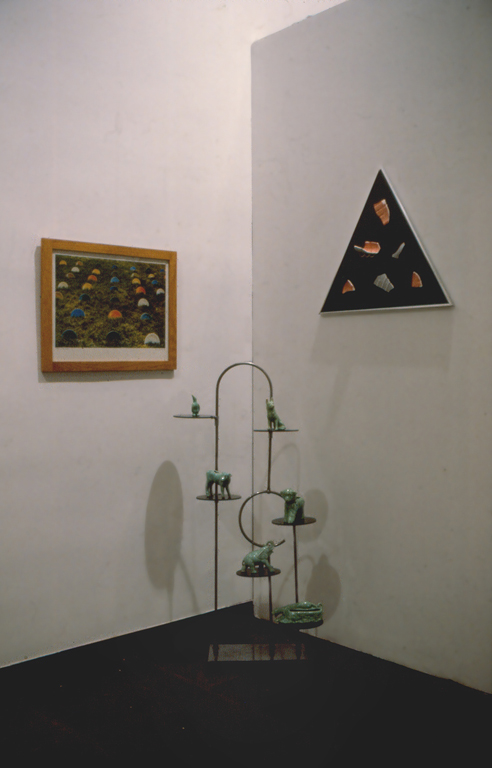 installation photo take of Anersons work at the ICA that includes the silk screen print Fiesta in the Grass, a work made from broken Red Wing Pottery and Formica and another of green animal planters on a deco bakery stand 