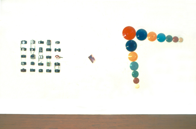 This photograph shows three works by Harry Anderson.  One made from cameras, a photograph and one from fiesta ware