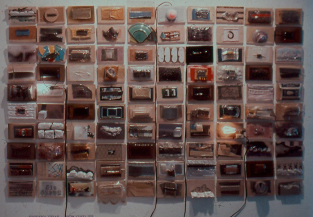 A wall piece by artist Harry Anderson made up of 100 individual vacuum formed plastic found object reliefs.  Titled 100 postcards
